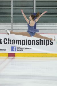 Figure skater Heather Smarick performing a split jump in an ISI ice skating competition